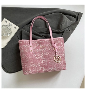 Detail of pink and white woven tote bag with a gold M letter metal pendant charm