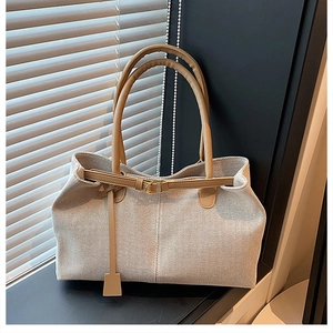 Close-up of cream canvas tote bag with leather straps and elegant gold metal buckles