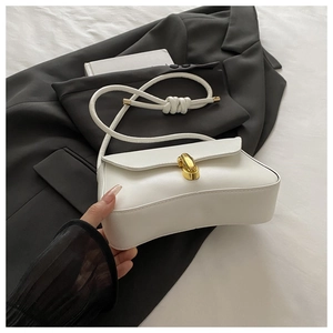 Detail of white leather shoulder bag with gold metal clasp and knotted strap on blazer