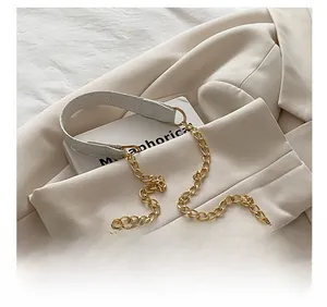 Detail of ivory woven shoulder bag featuring a wide leather strap and gold chain link