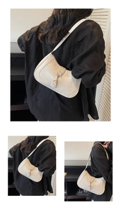 Close-up of white minimalist hobo bag featuring a decorative golden horsebit buckle