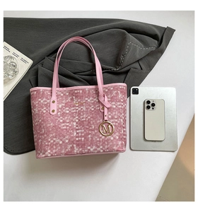 Pink woven tote bag featuring gold M-letter charm and brand logo with tablet for scale