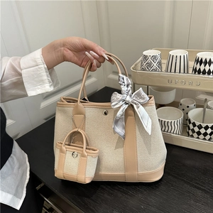 Chic canvas tote bag with brown leather trim and decorative silk scarf detail