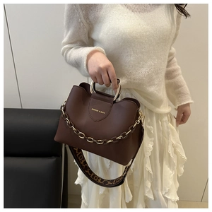 Dettaglio borsa a tracolla marrone scuro con manico ad anello dorato e tracolla jacquard