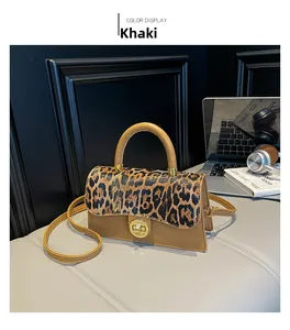 Khaki Handtasche mit Leopardenmuster und Metalldrehschloss auf grauem Schreibtisch