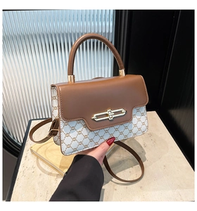 Detail of vintage crossbody bag showing monogram pattern with golden turn-lock closure