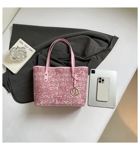 Detailed view of pink plaid tote bag with golden M charm and leather handles