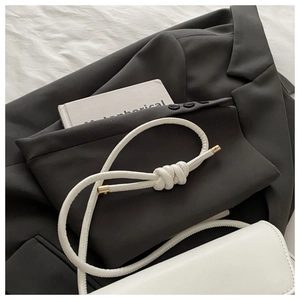 Macro shot of white leather square bag featuring a distinctive tubular knotted shoulder strap