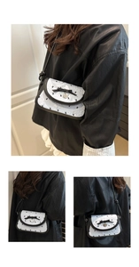 Détail d'un sac blanc avec nœud noir, pendentif en cœur et motifs de lapins imprimés