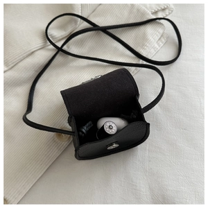Close-up of black leather mini crossbody bag holding lipstick and wireless earphones