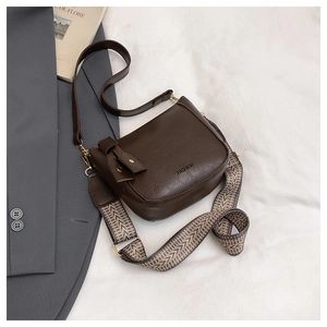 Detail of dark brown leather handbag featuring retro geometric woven wide shoulder strap