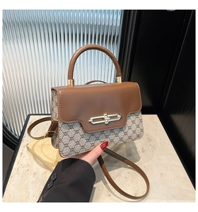 Detail of vintage crossbody bag with monogram pattern and gold metallic clasp closure