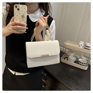 Close-up of white woven leather handbag with gold chain strap and metal clasp detail