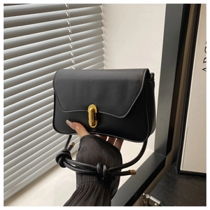 Detail of black leather crossbody bag featuring gold oval lock and knotted shoulder strap