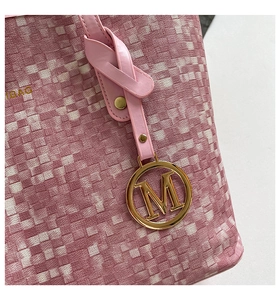 Detailed view of pink and white woven tote texture with golden letter M charm