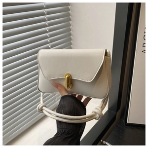 Detail of white leather shoulder bag featuring U-shaped gold lock and knotted strap