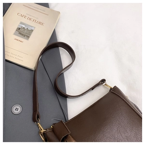 Detail of dark brown leather bucket bag with gold hardware and smooth polished finish