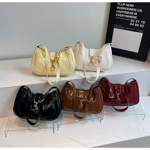 Minimalist half-moon underarm bags in five colors displayed on white tiered steps
