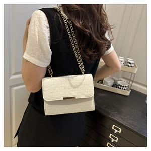 White quilted shoulder bag featuring gold chain strap and minimalist metal bar detail