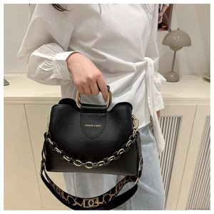 Dettaglio borsa tote nera con manici a U dorati e catena decorativa elegante