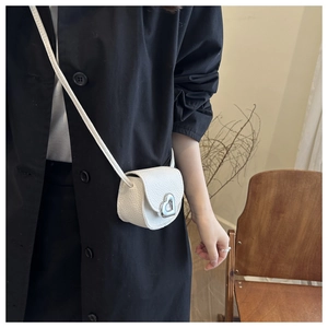Close-up of white pebble leather bag featuring a silver heart-shaped metal buckle