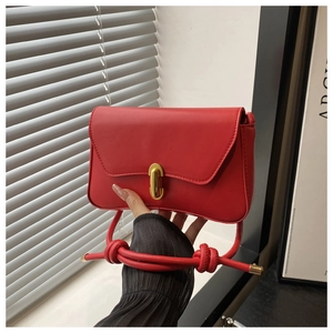 Close-up of red leather handbag with gold metal lock and knotted strap detail