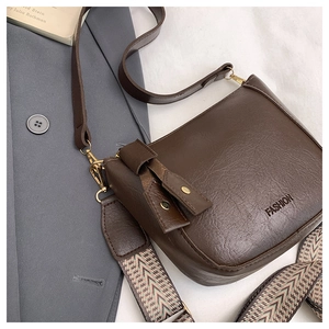 Detail view of dark coffee bucket bag with stylish geometric woven wide shoulder strap