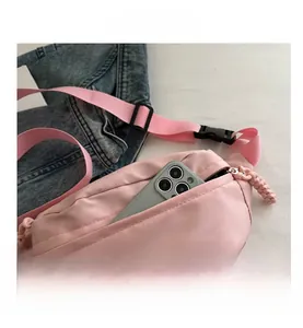 Close-up of pink nylon crossbody bag showing smartphone storage and woven zipper pull