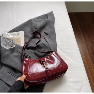 Détail du sac baguette en cuir verni bordeaux avec boucle en métal doré vintage