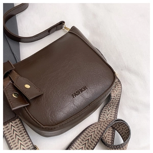 Detail of dark brown lychee textured bag with boho geometric wide strap and fashion logo