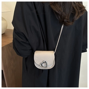 Detail of beige lychee leather mini bag with silver heart metal clasp on black shirt