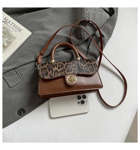 Détail du sac à rabat léopard avec fermoir doré à côté d'un téléphone portable
