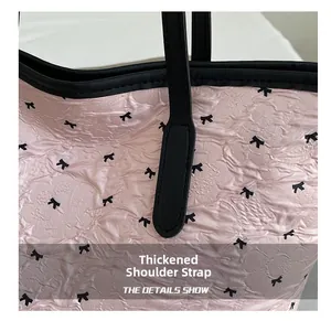 Close-up of pink puckered fabric tote bag with black bow print and reinforced straps