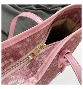 Close-up of golden zipper closure on pink woven tote bag with leather piping detail