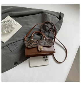 Sac brun avec rabat léopard et fermoir doré à côté d'un smartphone pour comparer la taille