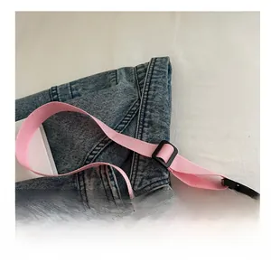 Close-up of pink woven shoulder strap with adjustable black plastic buckle and clasp