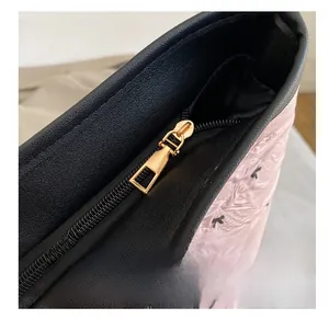 Detail of a smooth golden zipper on pink quilted fabric with black letter k pattern