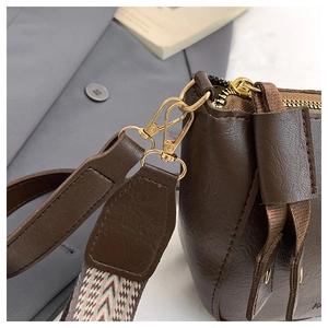 Detail of dark brown leather handbag with golden hardware and ethnic woven shoulder strap