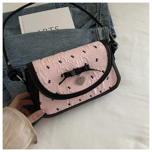 Détail du sac à main rose plissé avec nœud noir et pendentif cœur en argent poli