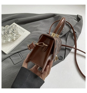 Vue latérale du sac en cuir marron à motifs avec boucle en métal et bandoulière