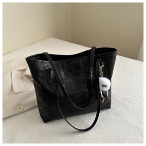 Detail of black houndstooth embossed tote bag with fuzzy charm and fashion patch