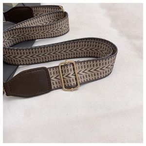 Close-up of retro woven shoulder strap with geometric patterns and gold metal buckles