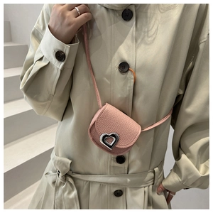 Détail du sac de selle rose avec fermoir en forme de coeur argenté sur manteau