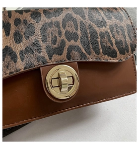 Gros plan sur le motif léopard et le fermoir rotatif doré de ce sac à main chic