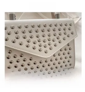 Macro view of white leather handbag with stylish silver metal rivets and envelope flap design