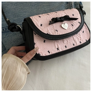 Gros plan d'un sac plissé rose avec nœud noir et pendentif métallique en forme de cœur