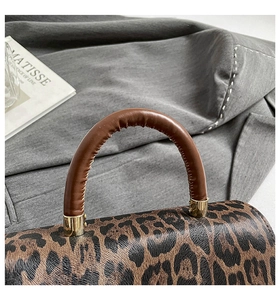 Gros plan du sac à main léopard avec poignée en cuir marron et boucles dorées
