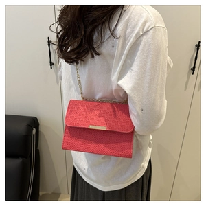 Detail of coral red woven texture on crossbody bag with gold chain strap