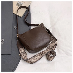 Detail of coffee leather bucket bag with wide ethnic strap and gold metal hardware