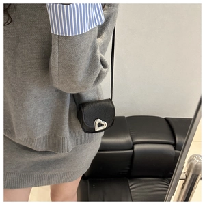 Detail of black pebbled leather mini crossbody bag featuring a silver heart-shaped clasp
